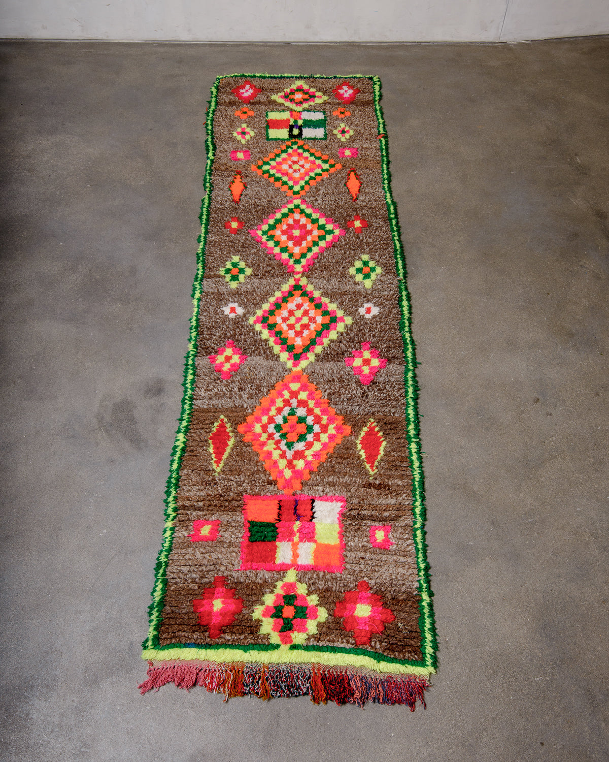 Berberlin vintage runner rug with brown wool and neon cotton, laying flat on concrete floor.